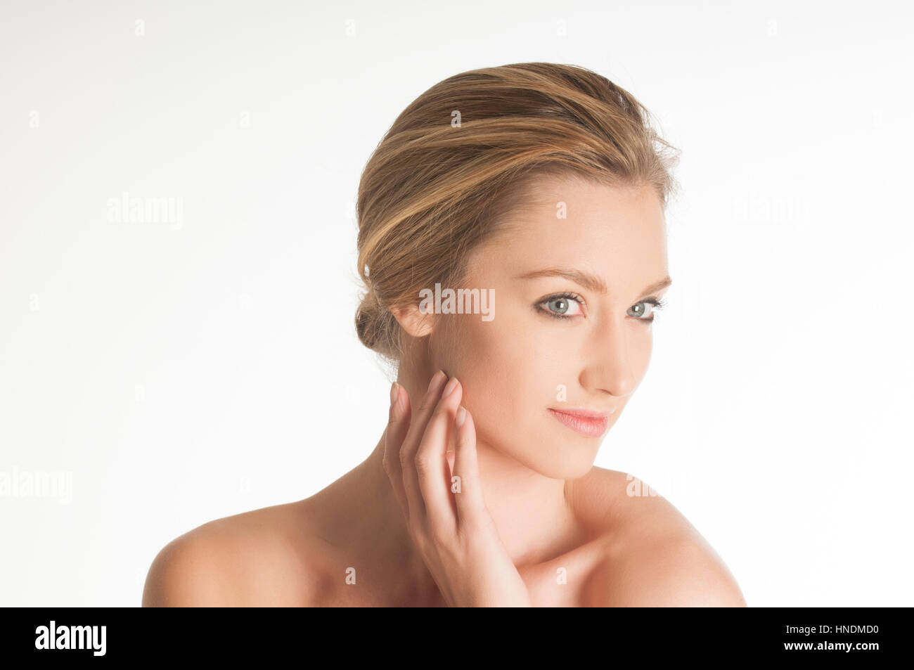 Bella giovane donna canto di toccare la faccia che guarda lontano sorridente contro uno sfondo bianco Foto Stock