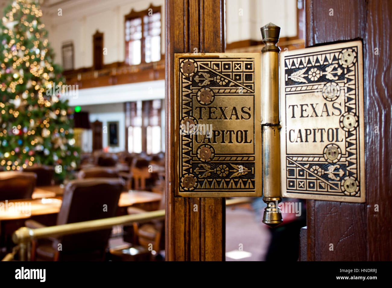 Un particolare di una cerniera della porta in Texas State Capitol Building con un albero di Natale illuminato in background. Foto Stock