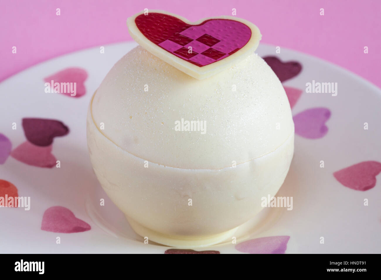 M&S Lampone e sfere di Prosecco per dessert per il giorno di San Valentino sul piatto decorativo con cuori impostato su sfondo rosa Foto Stock