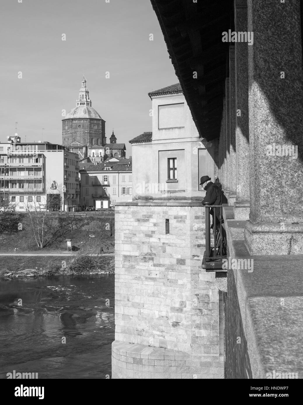 Pavia - Marzo 8, 2015: ponte coperto sul fiume Ticino. Il vecchio uomo con cappello scuro a guardare il fiume che scorre sotto il ponte. Foto Stock