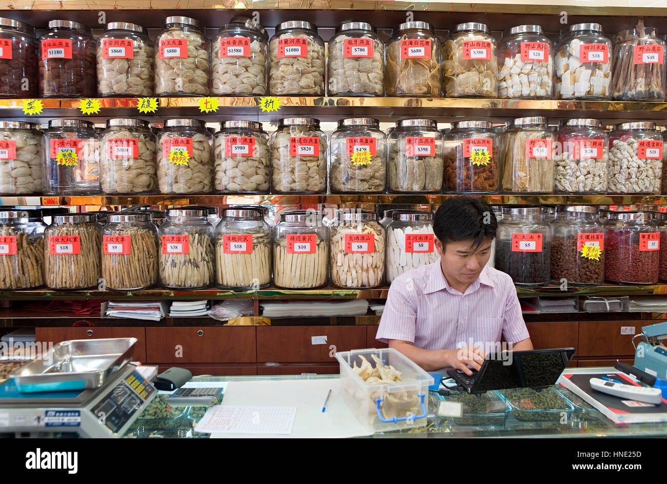 La medicina cinese, farmacia, l'uomo la lettura di computer nel suo negozio,Rua dos Mercadores,Macao,Cina Foto Stock