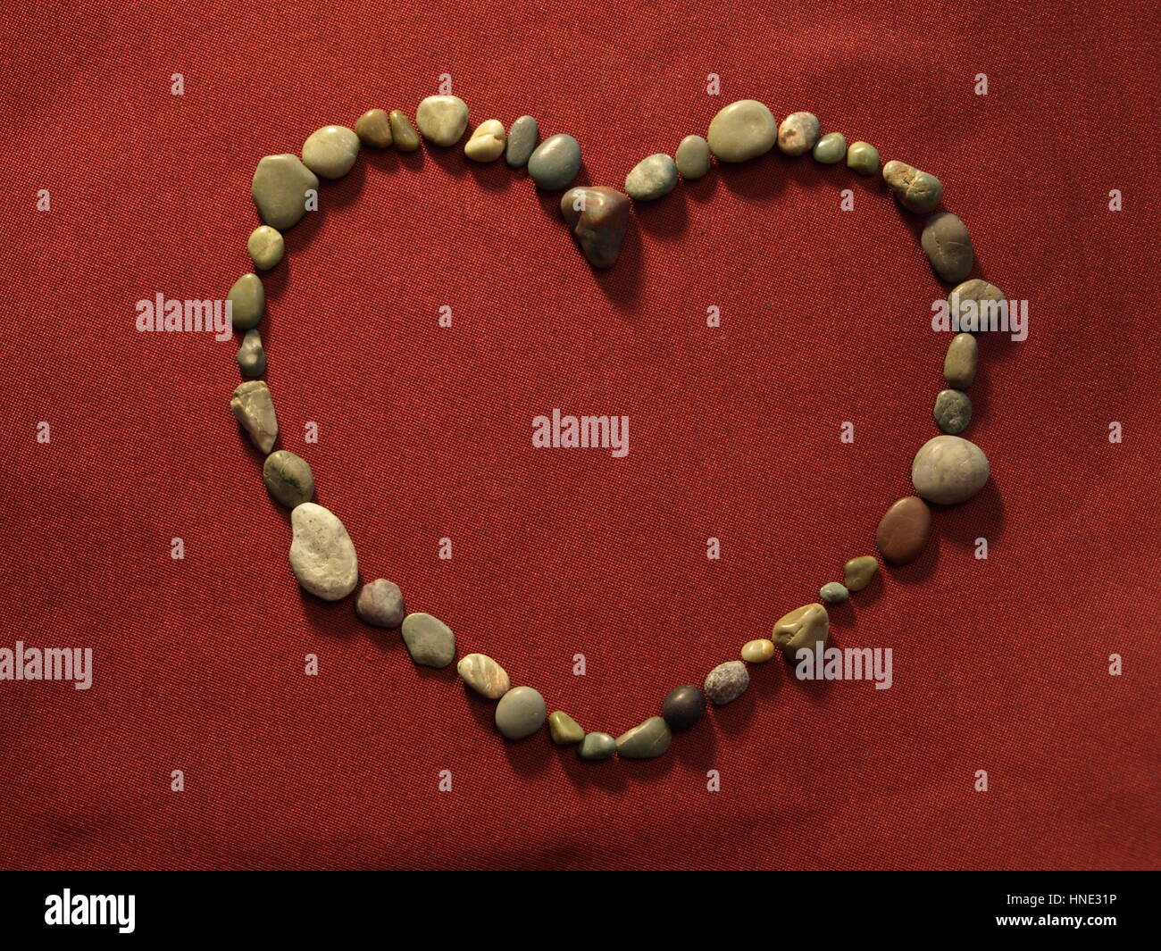 Un cuore di pietre su raso rosso - California di giada e le Pietre di luna Foto Stock