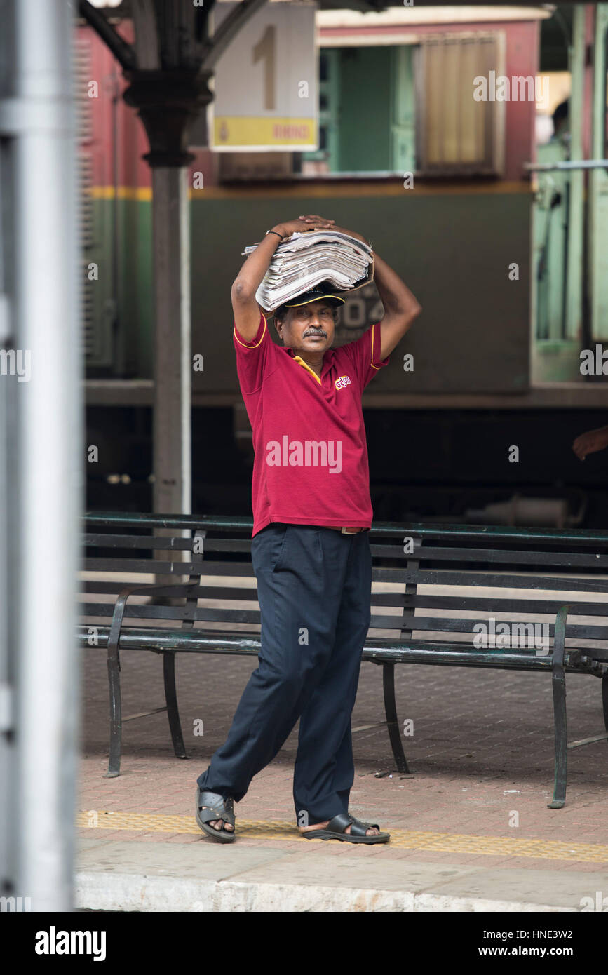 Venditore a vendere giornali, Kandy stazione ferroviaria, Kande, Sri Lanka Foto Stock