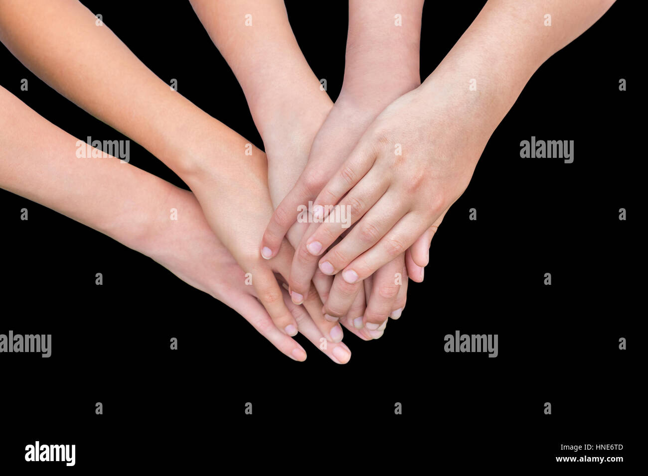 Cinque bracci di ragazze con le mani sulla parte superiore di ogni altro isolato su sfondo nero Foto Stock