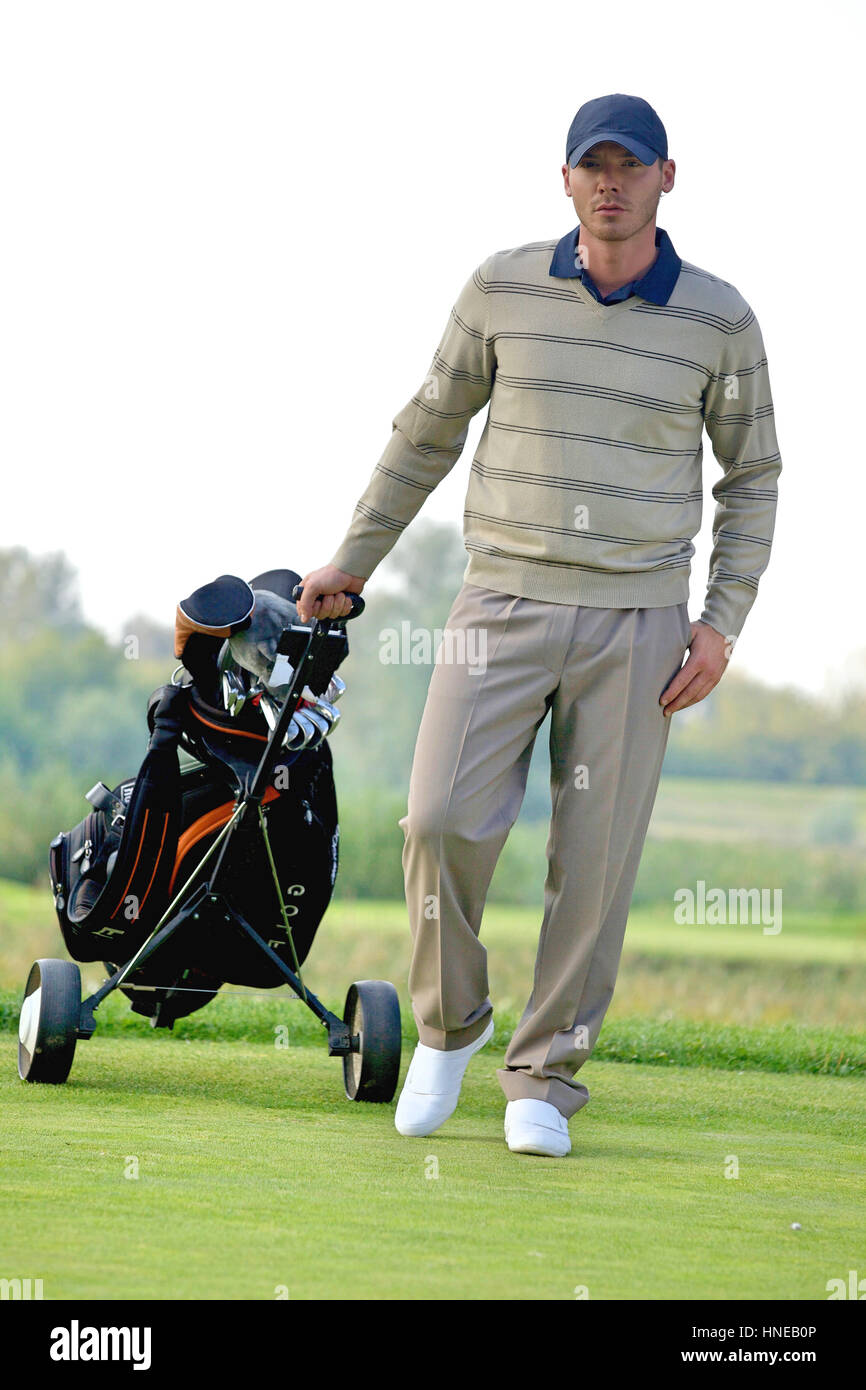 Ritratto di giovane uomo che porta il trolley con borsa da golf Foto Stock