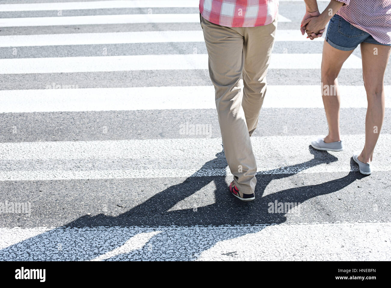 Sezione bassa del giovane a camminare su crosswalk Foto Stock