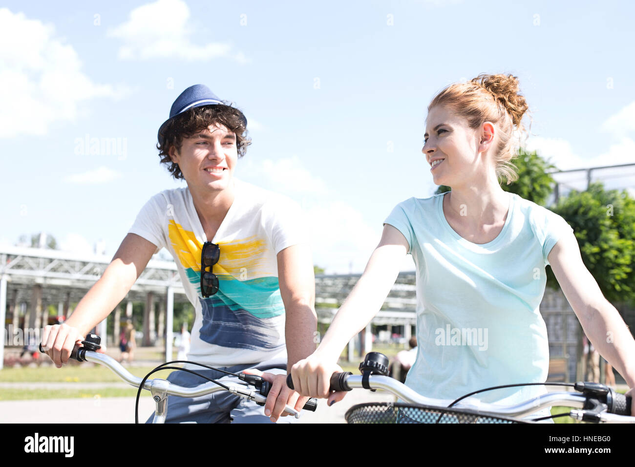 Sorridente giovane guardando gli uni con gli altri mentre escursioni in bicicletta in città Foto Stock