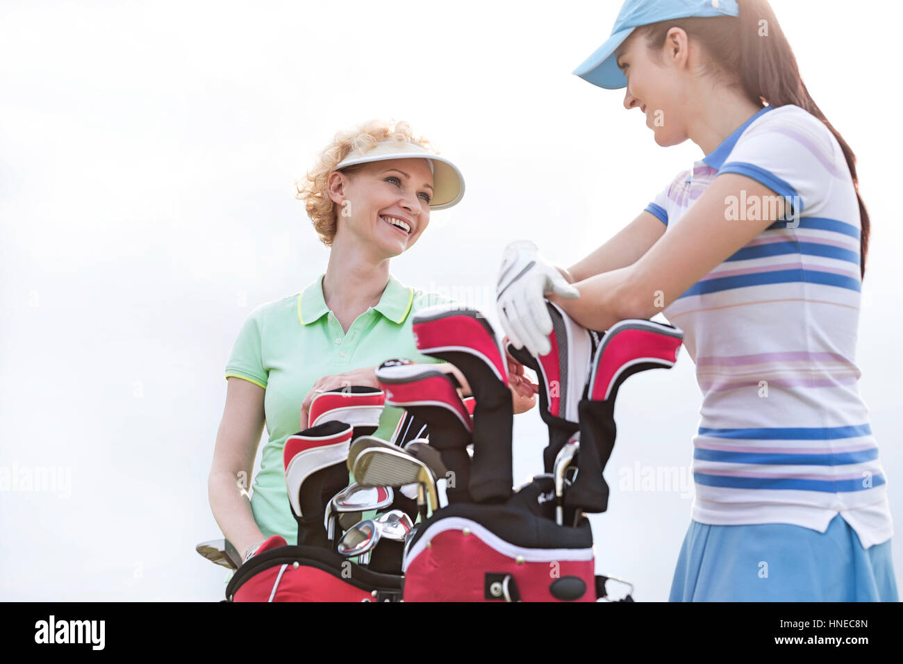 Basso angolo vista di felice golfisti femmina parlando contro il cielo chiaro Foto Stock