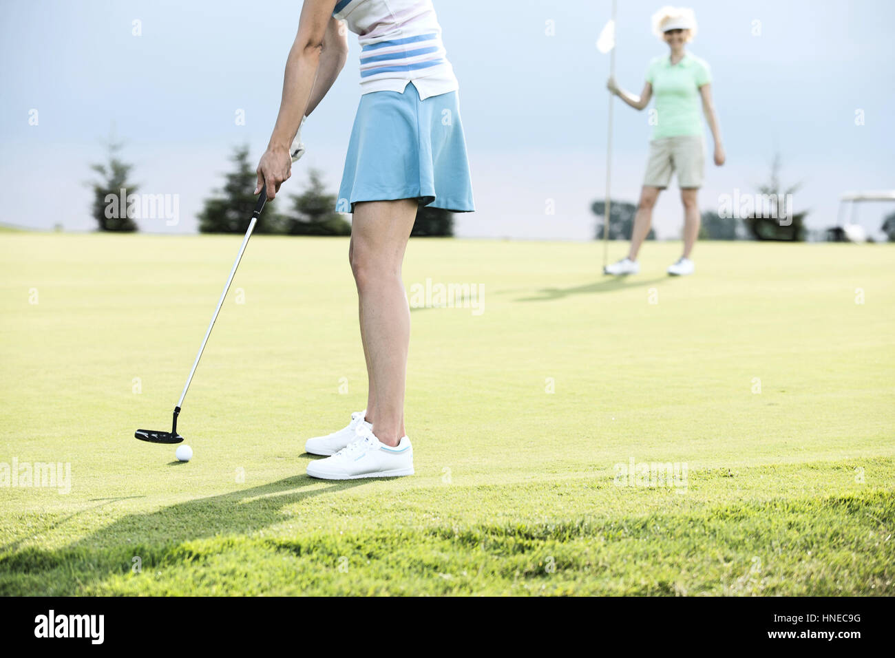 Sezione bassa della donna che gioca a golf con amico femmina Foto Stock