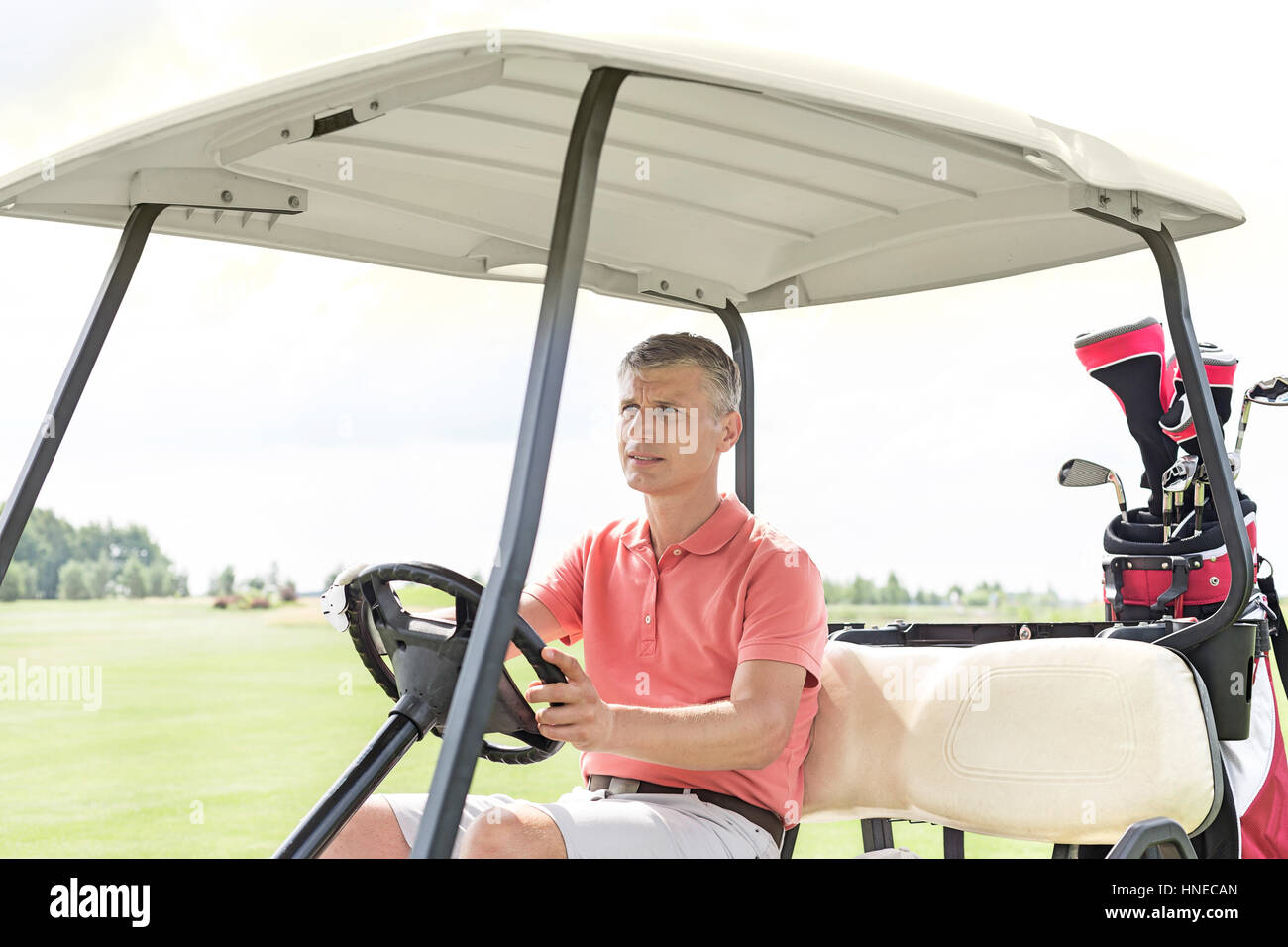 Uomo di mezza età la guida carrello a campo da golf Foto Stock