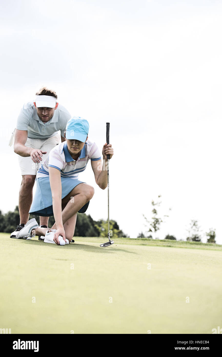 Uomo Donna assistenza immissione palla sul campo da golf contro sky Foto Stock