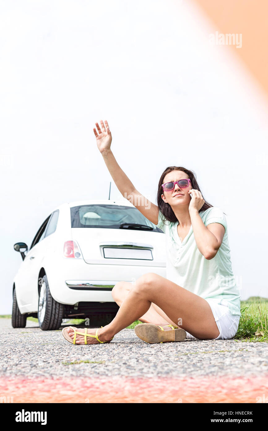 Frustrati donna autostop durante l'utilizzo di telefono cellulare da ripartiti in auto Foto Stock