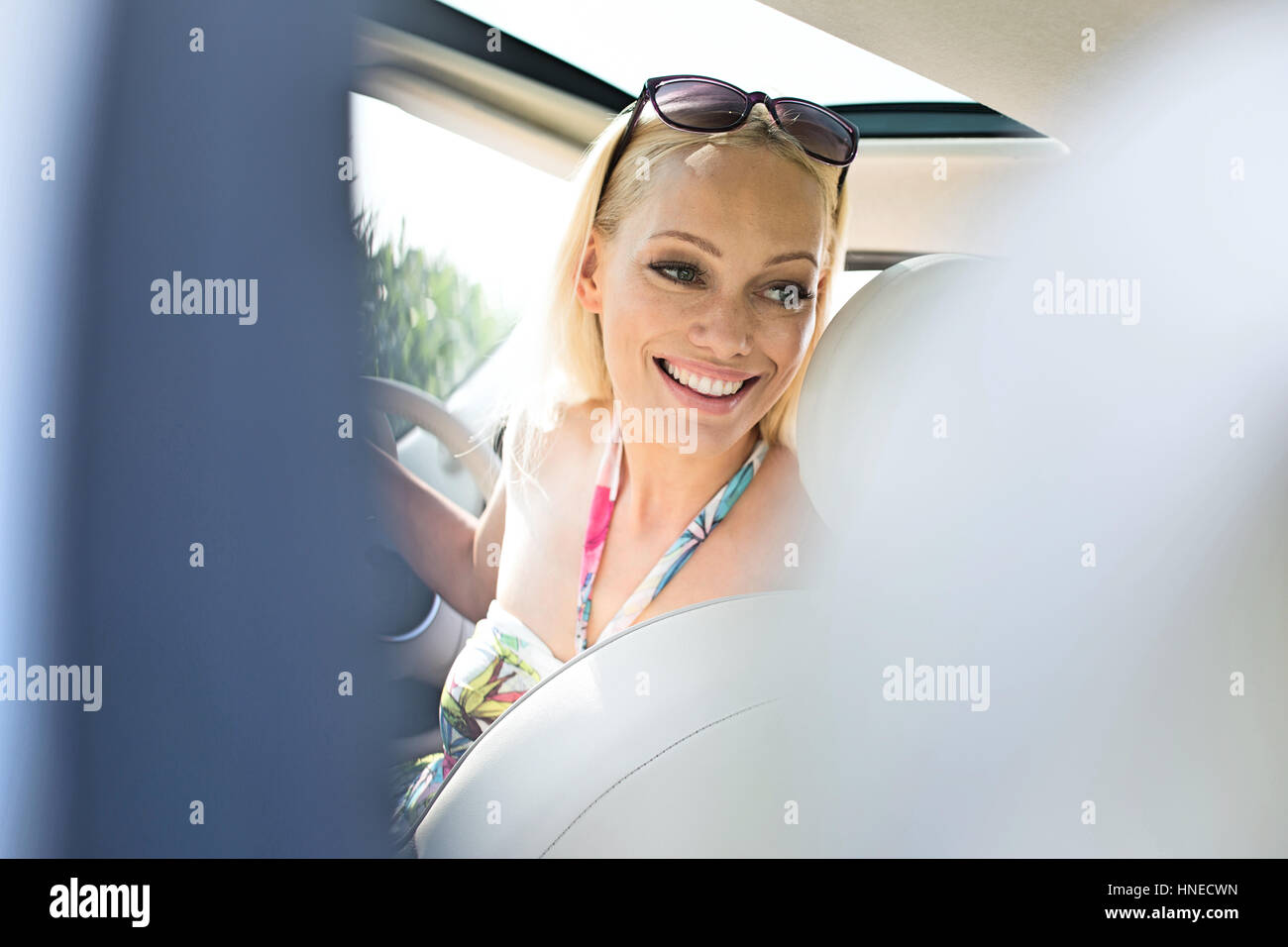 Felice bella donna guardando indietro mentre si guida auto Foto Stock