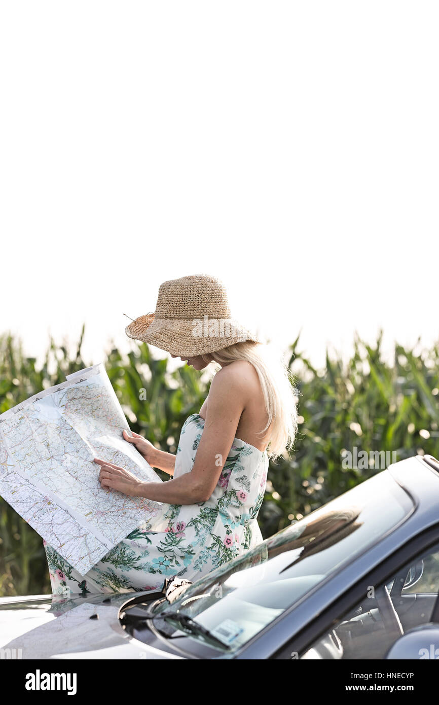 Donna mappa di lettura pur poggiando su cabriolet Foto Stock