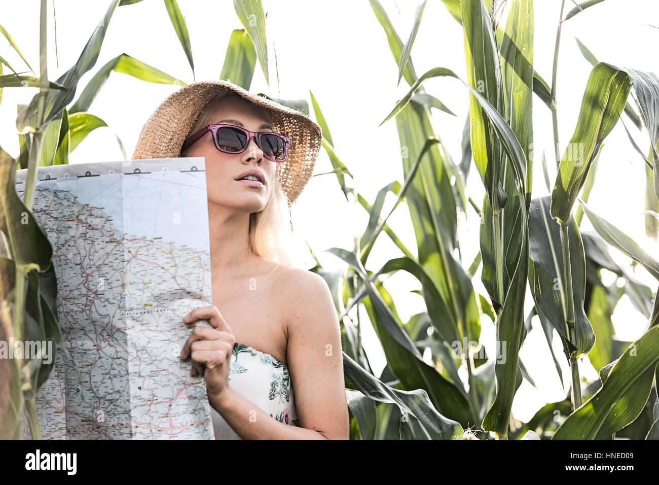 Donna che mantiene mappa stando in piedi in mezzo a piante all'aperto Foto Stock