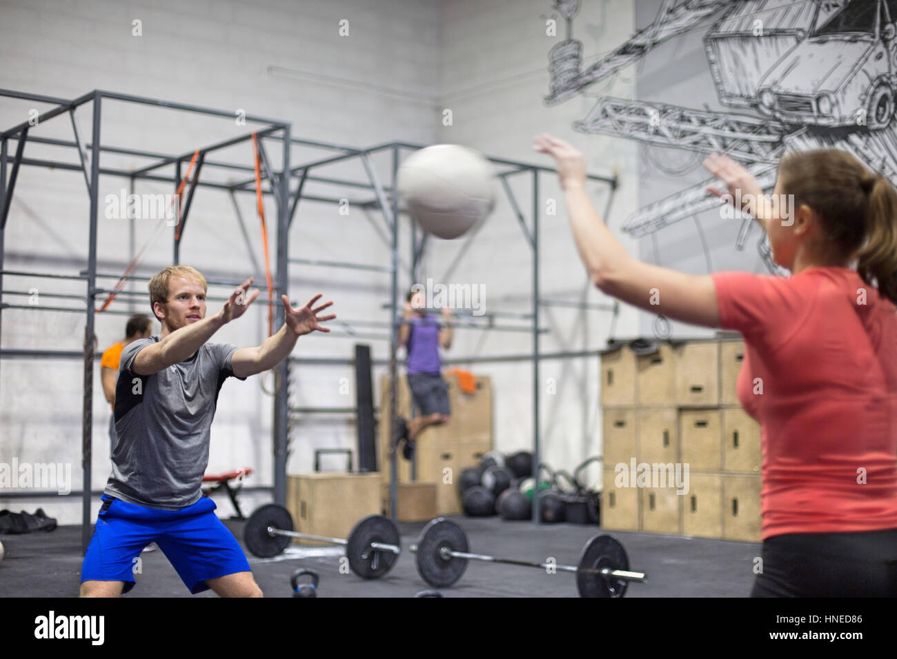 Uomo Medicina lanciando la palla verso la donna in palestra crossfit Foto Stock