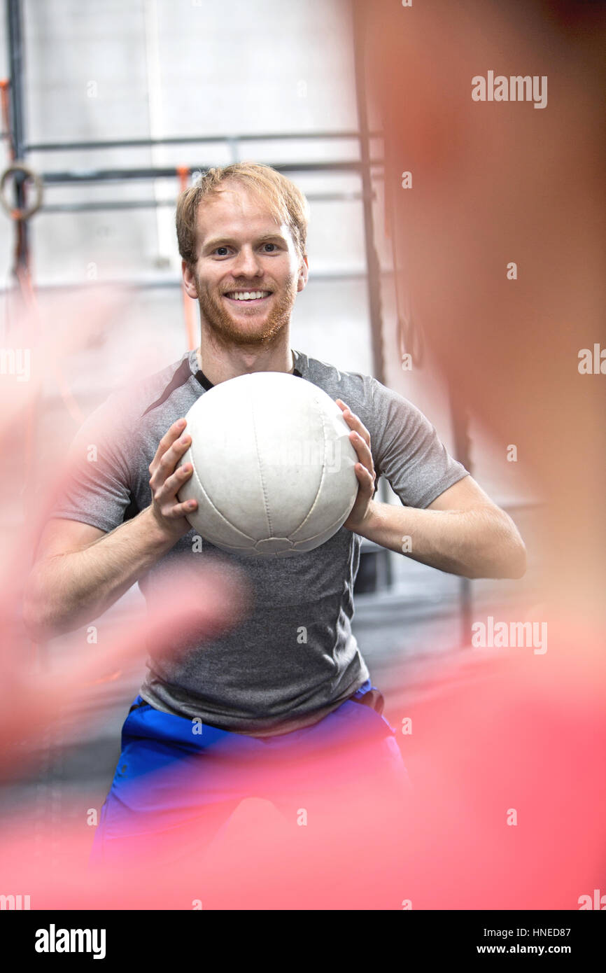 Felice l'uomo medicina lanciando la palla verso la donna in palestra crossfit Foto Stock