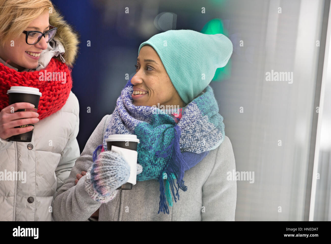 Felici donne guardando ogni altro tenendo tazze monouso Foto Stock