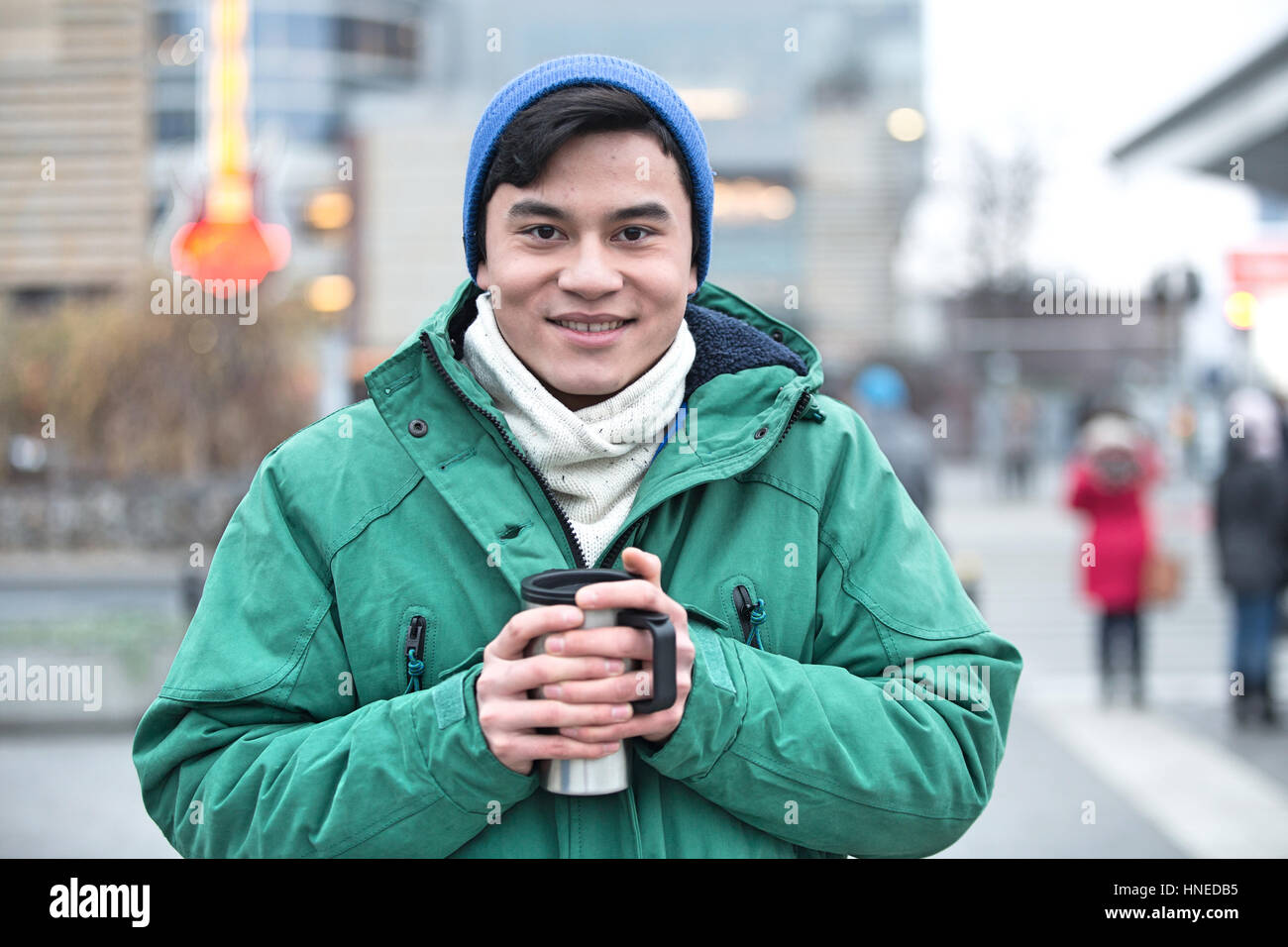 Ritratto di uomo in abbigliamento invernale sorridente su una strada di città Foto Stock