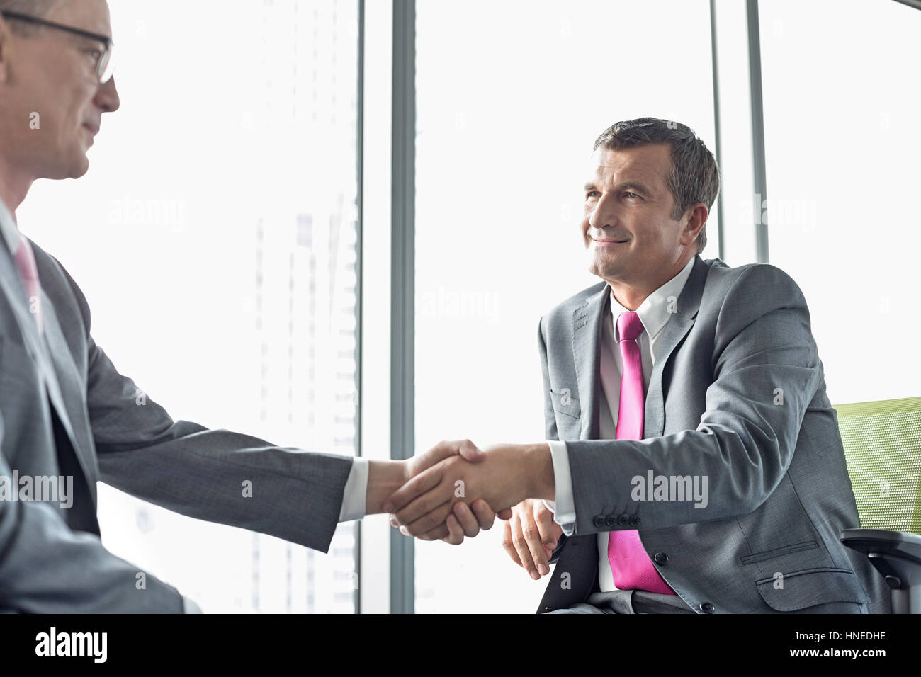 Imprenditori maturi stringono le mani in office Foto Stock
