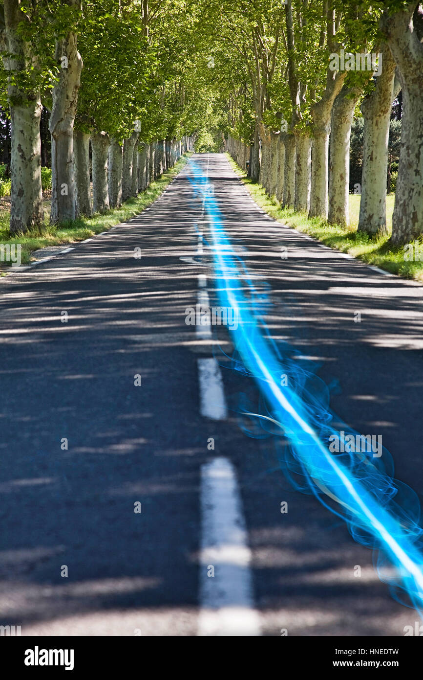Blue Streak di luce sulla strada di campagna lungo gli alberi Foto Stock