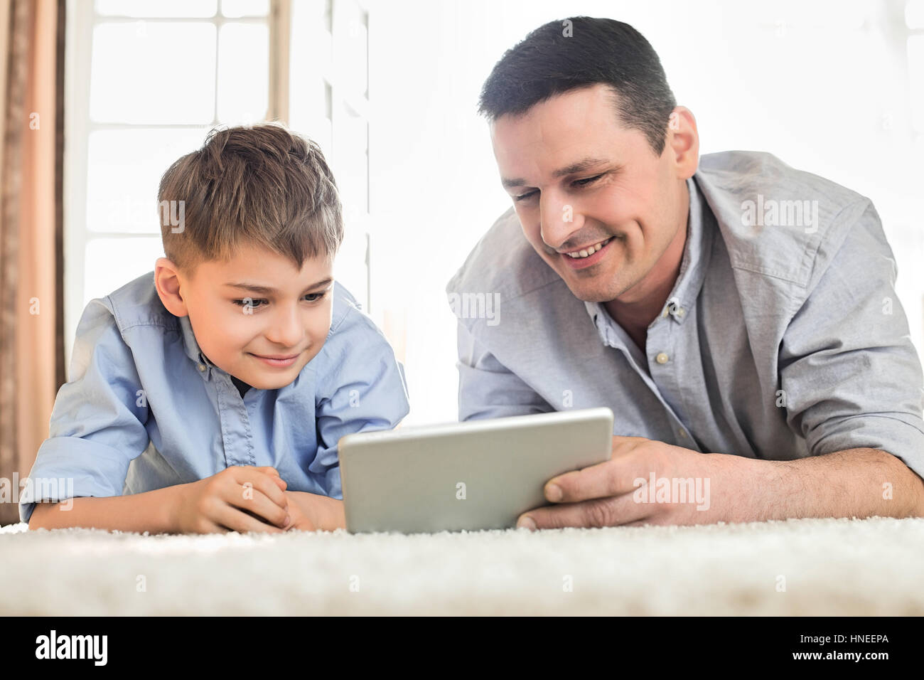 Padre e figlio utilizzando il tavolo digitale sul pavimento a casa Foto Stock