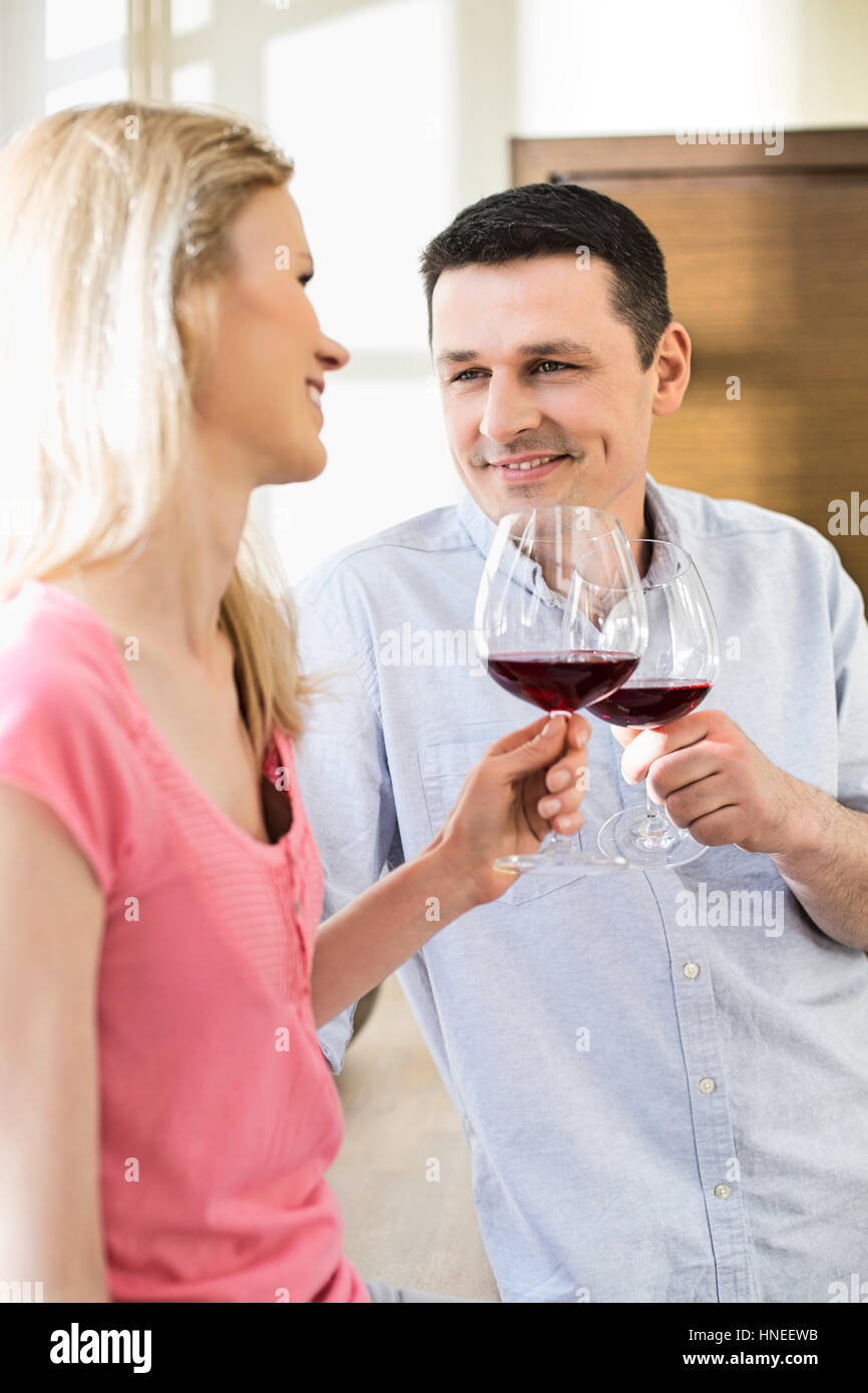 Felice coppia rosso di tostatura bicchieri di vino in cucina Foto Stock