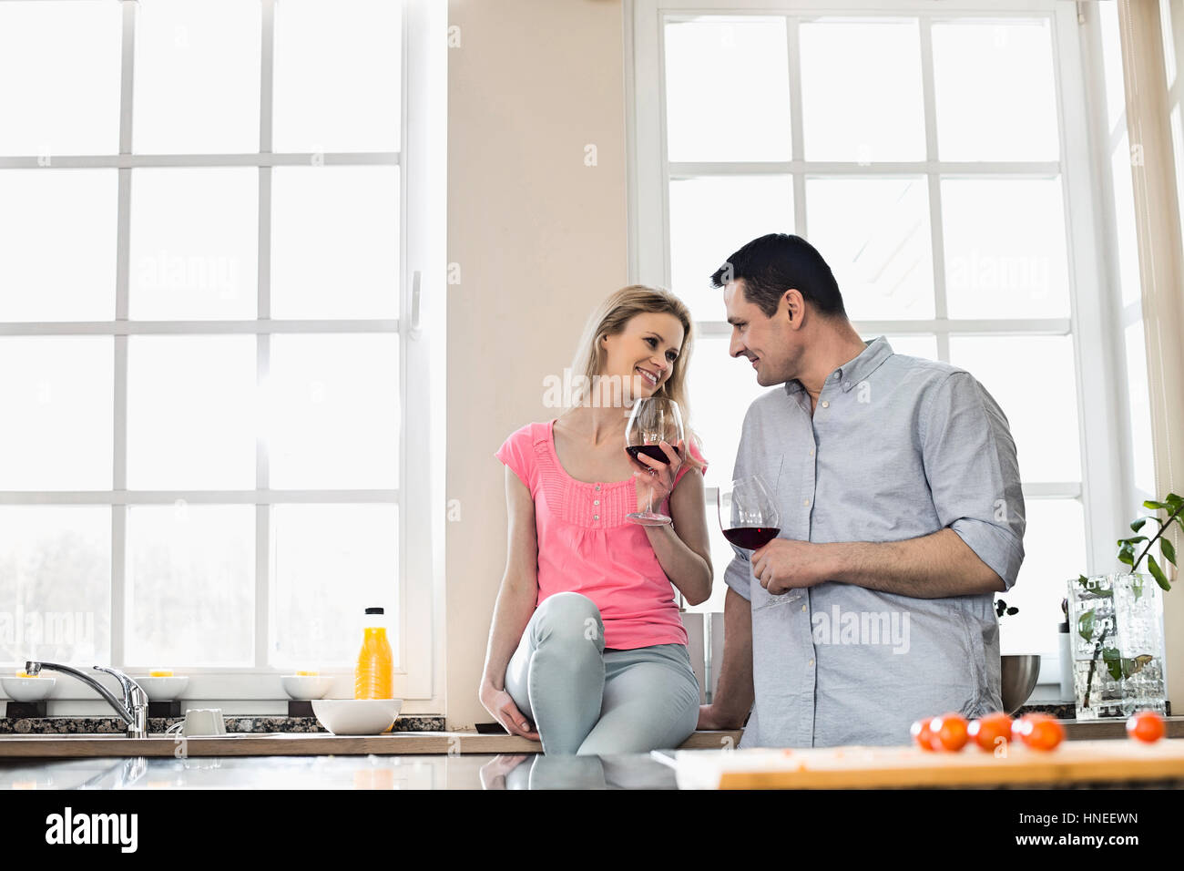 Coppia felice guardando ogni altro mentre si beve il vino rosso in cucina Foto Stock
