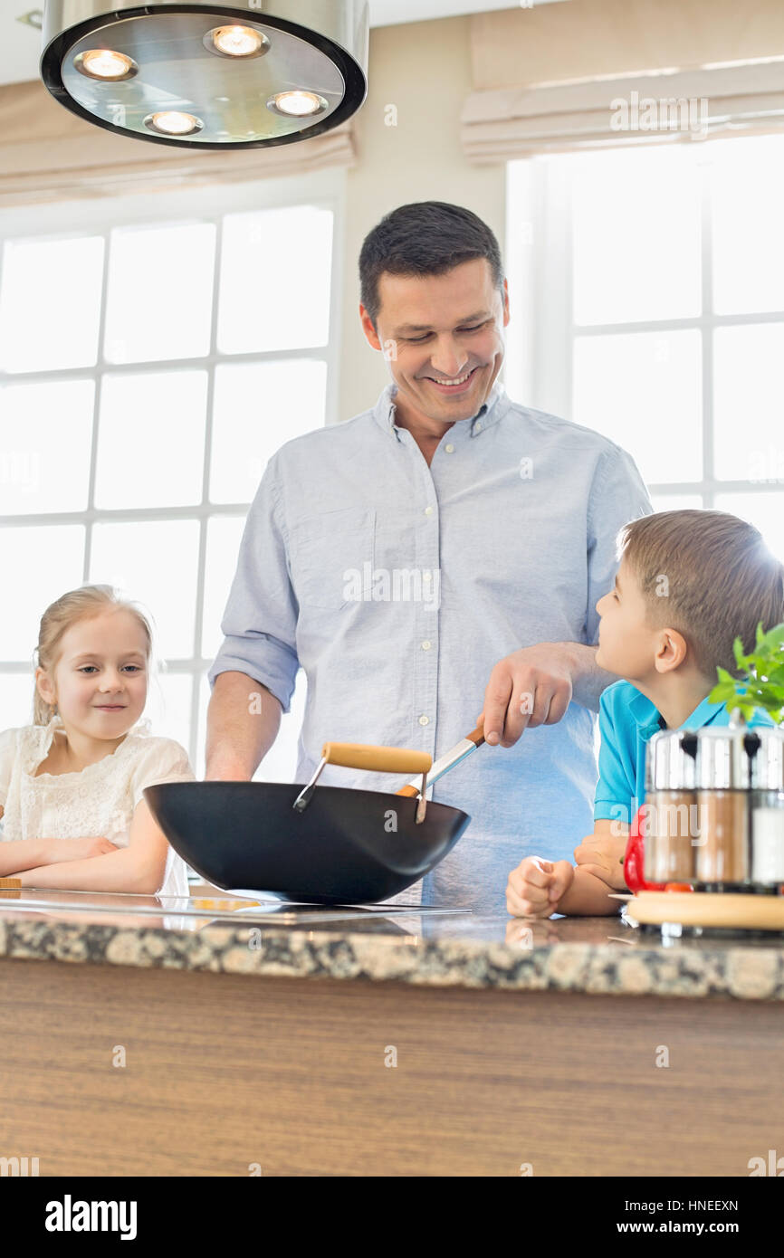 Uomo felice con i bambini nella preparazione degli alimenti in cucina Foto Stock
