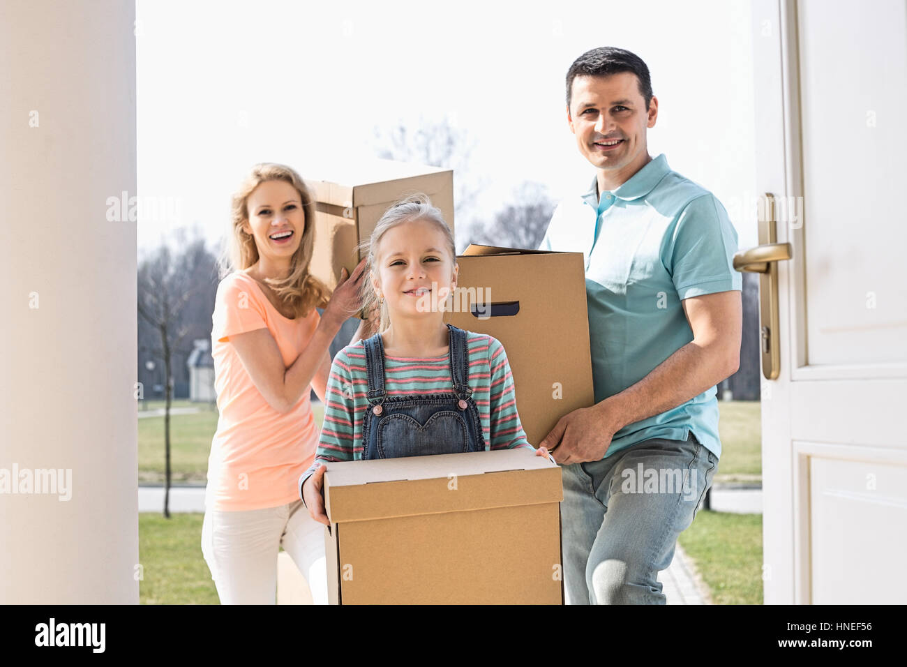 La famiglia felice con scatole di cartone immettendo il nuovo home Foto Stock