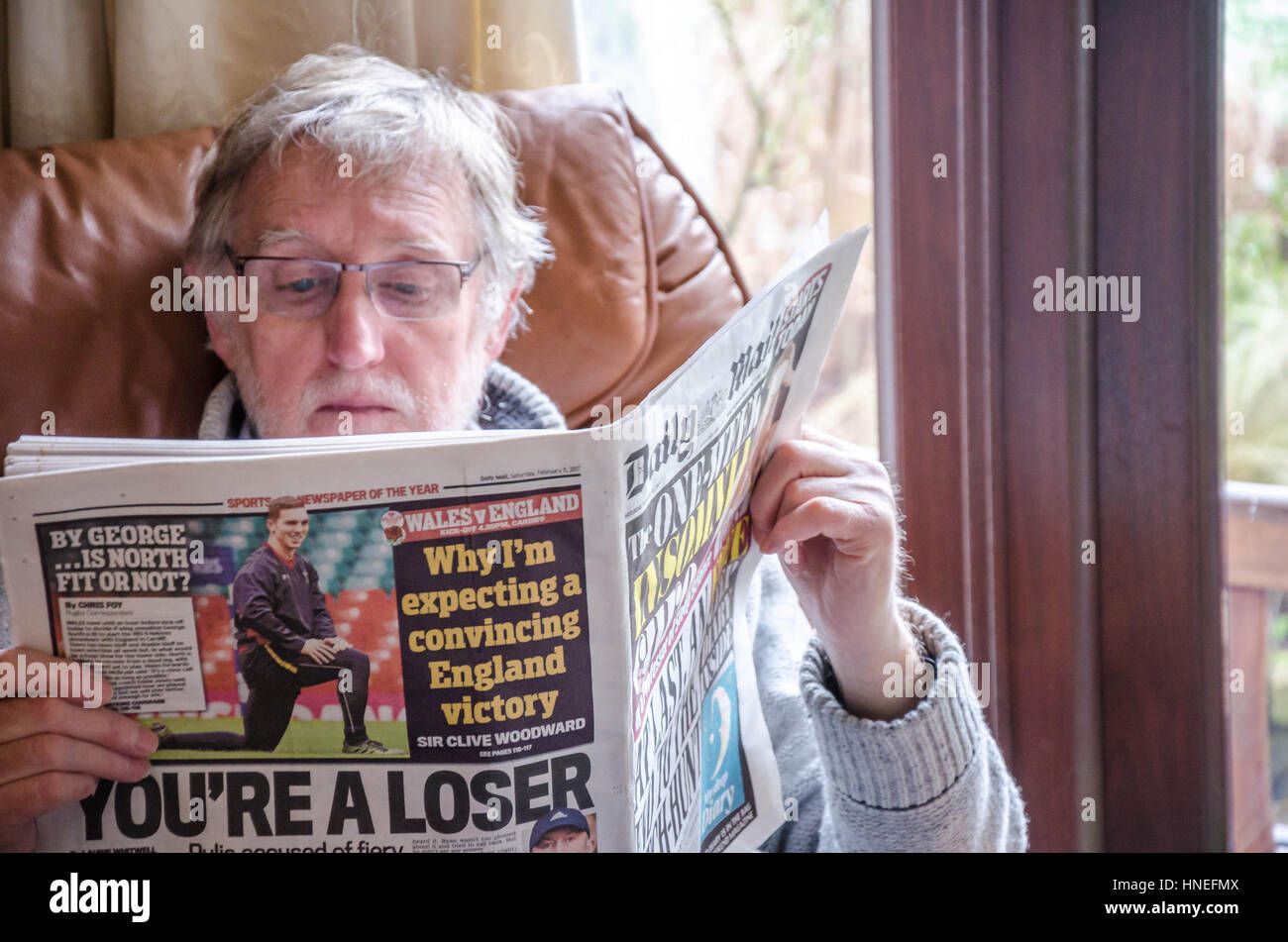 Un uomo si siede in Ann poltrona leggendo il quotidiano Daily Mail Foto Stock