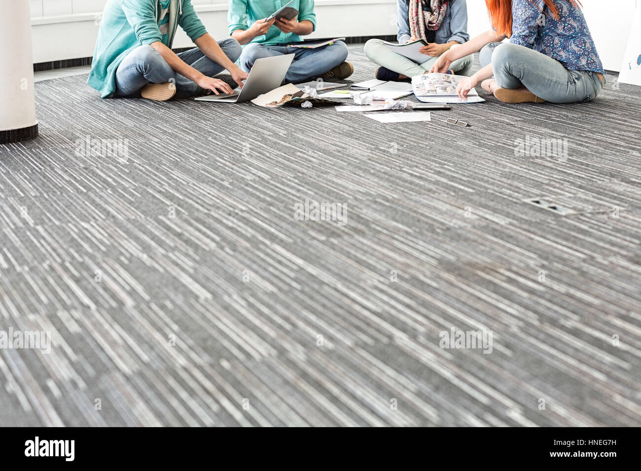 Sezione bassa di imprenditori lavora su pavimento in ufficio creativo Foto Stock