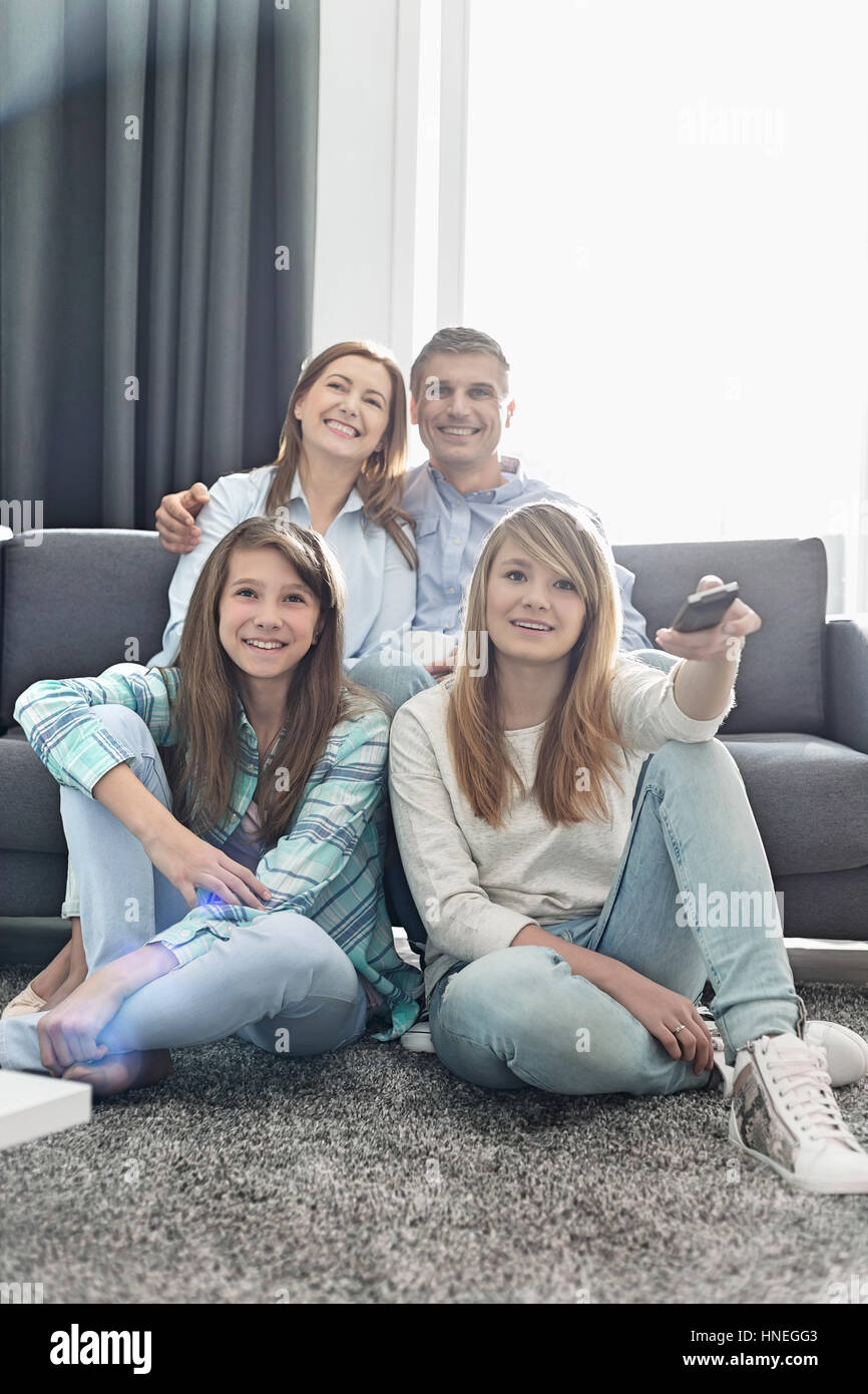 La famiglia felice di quattro guardando la TV insieme a casa Foto Stock