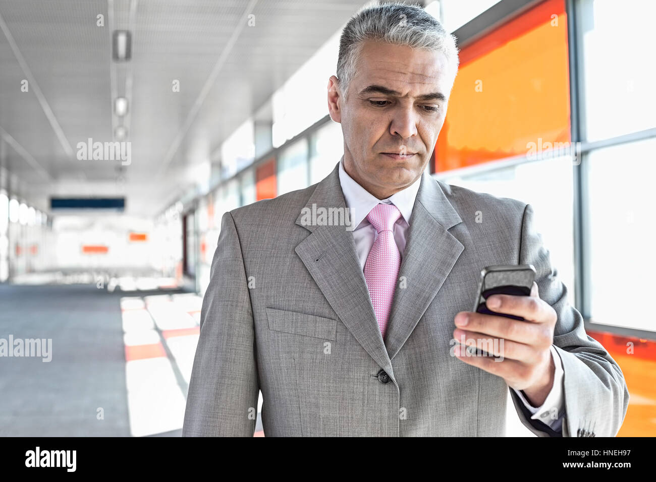 Persone di mezza età imprenditore della messaggistica di testo tramite telefono cellulare alla stazione ferroviaria Foto Stock