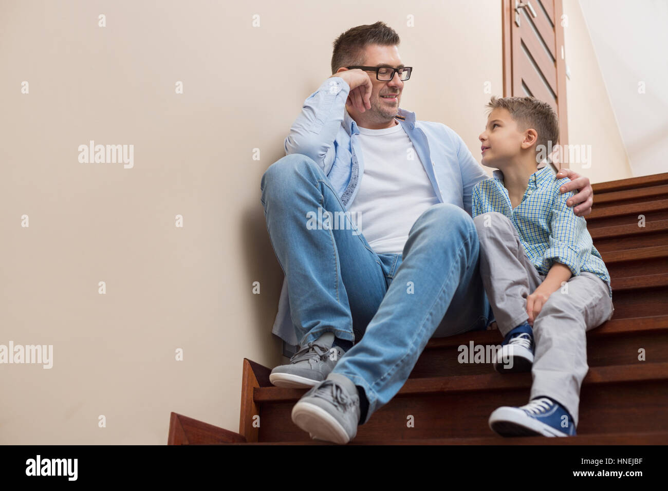 Lunghezza completa di padre e figlio guardando ogni altro mentre è seduto sui gradini a casa Foto Stock