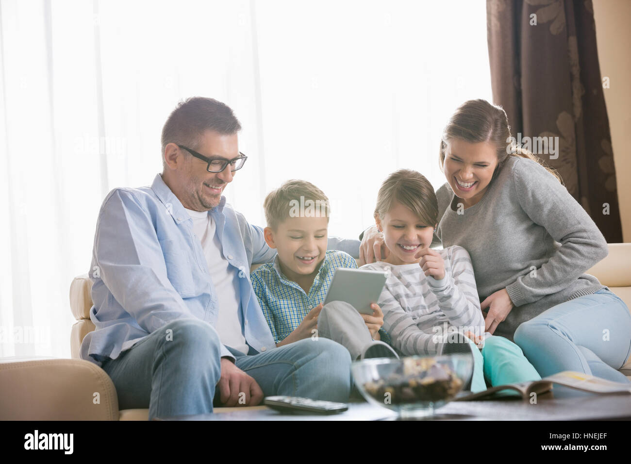 Famiglia allegra utilizzando tablet PC insieme nel soggiorno Foto Stock