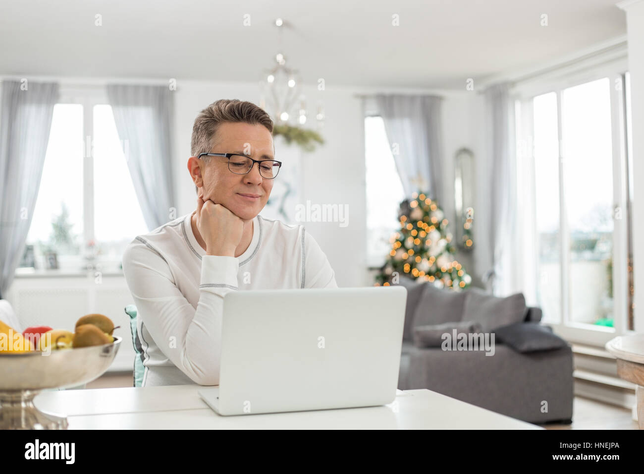 Uomo sorridente con notebook a casa Foto Stock