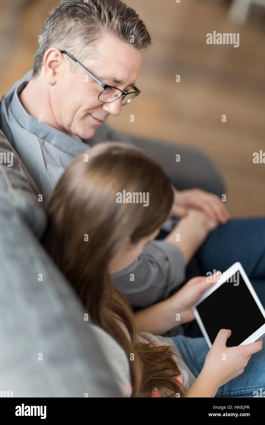 Elevato angolo di visione del padre e figlia con tavoletta digitale in casa Foto Stock