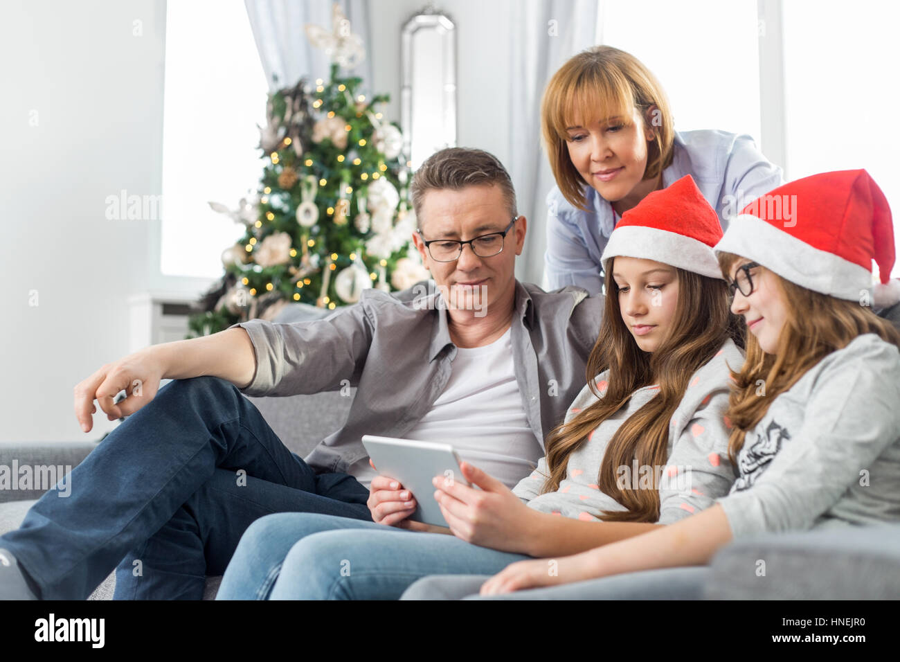 Famiglia di quattro persone con tavoletta digitale a casa durante il periodo di Natale Foto Stock