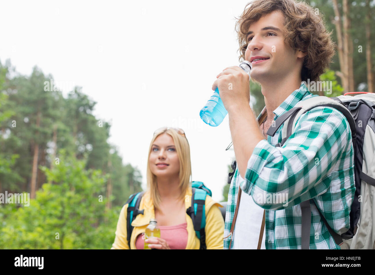 Escursionismo coppia bere bevande energetiche in foresta Foto Stock