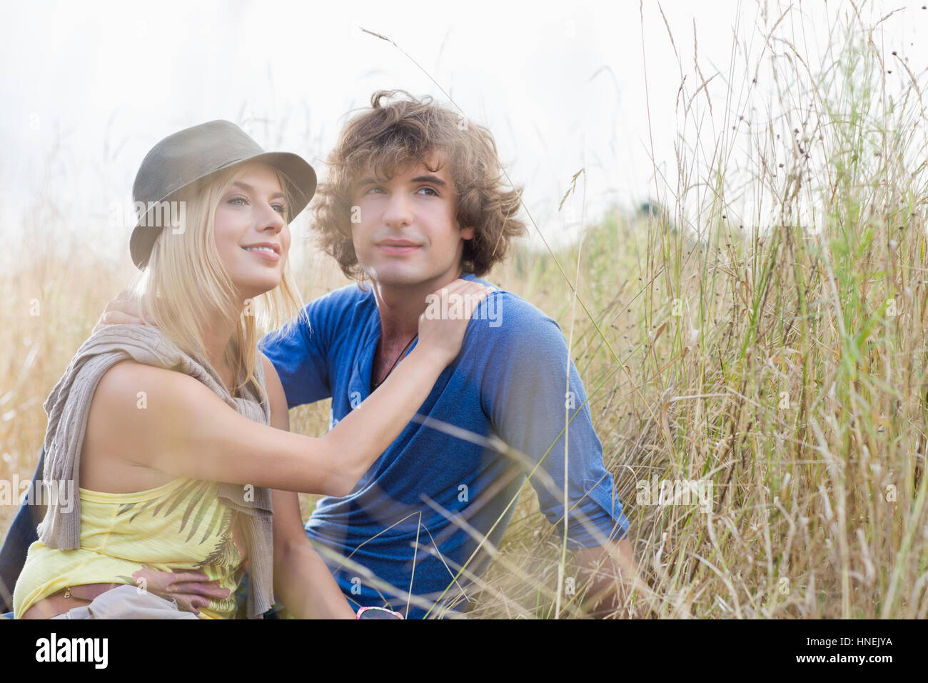 Amare giovane coppia in cerca di distanza mentre sedendo nel campo Foto Stock