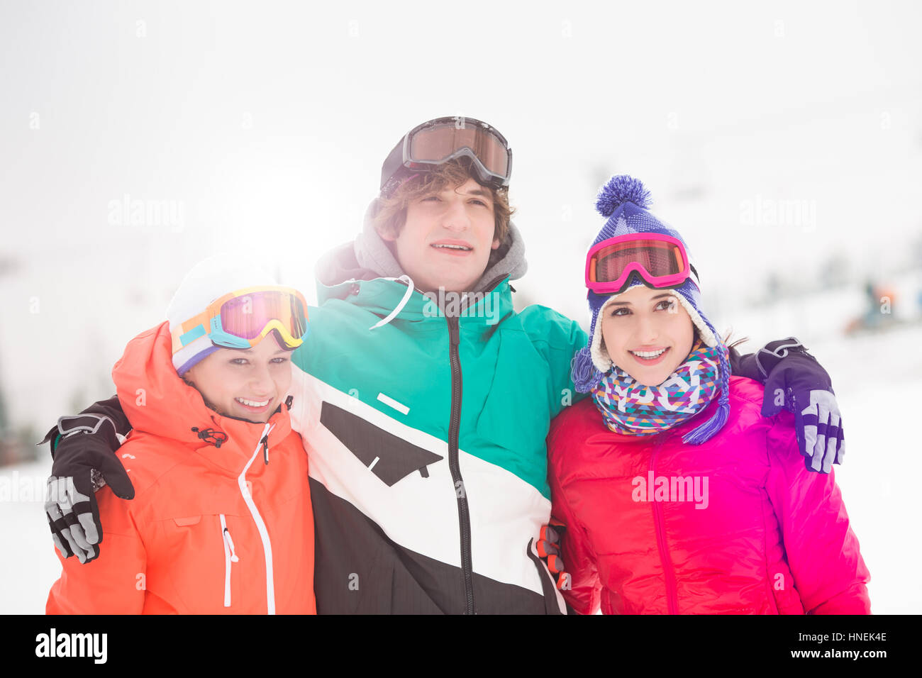 Felice giovane con amici di sesso femminile in piedi braccio intorno nella neve Foto Stock