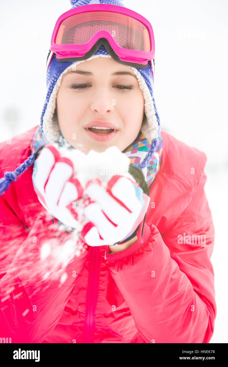 Giovane donna indossa cappotto invernale lavori di soffiaggio della neve all'aperto Foto Stock