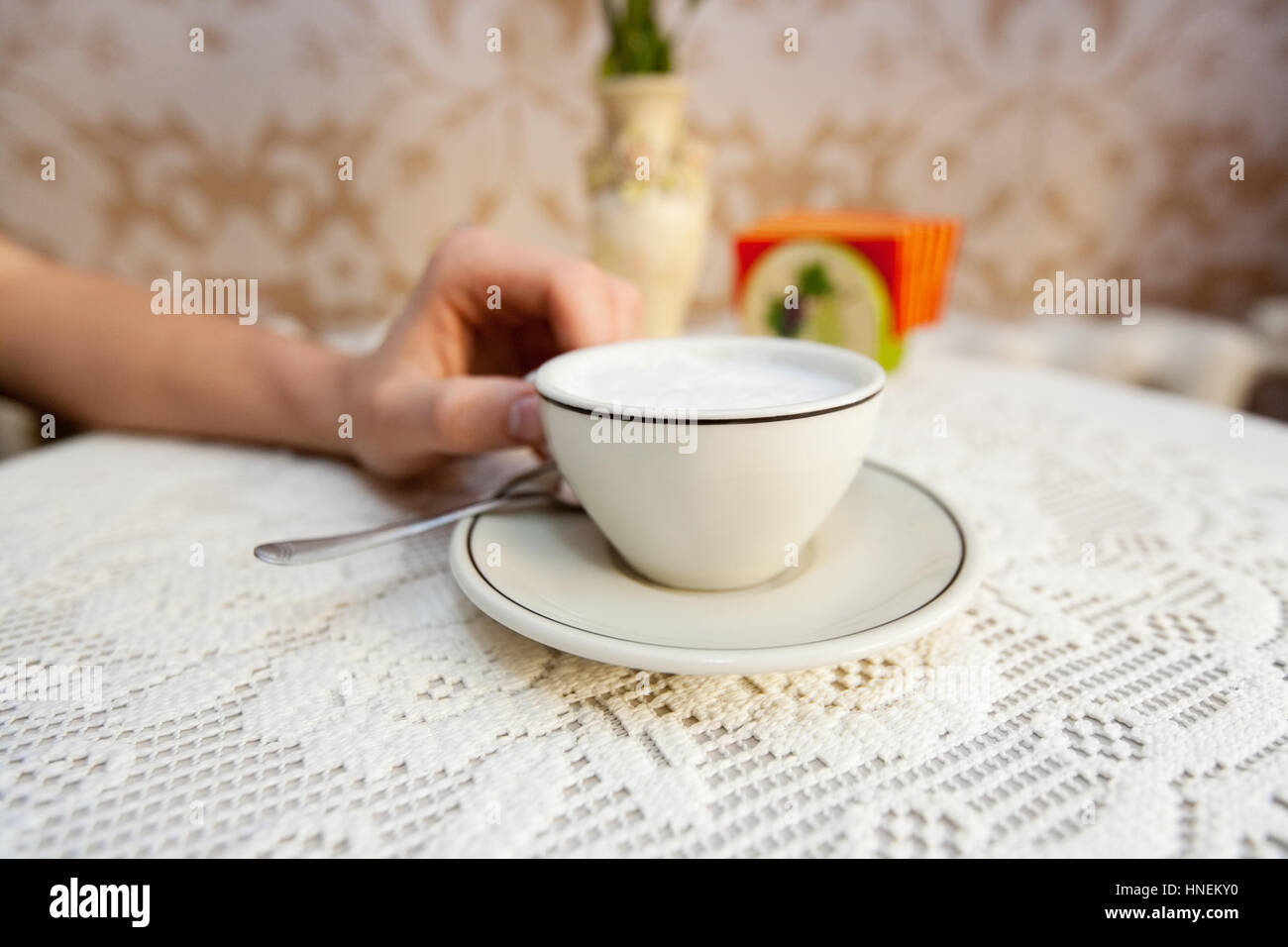 Immagine ritagliata dell'uomo avente tazza di caffè al tavolo in cafe Foto Stock