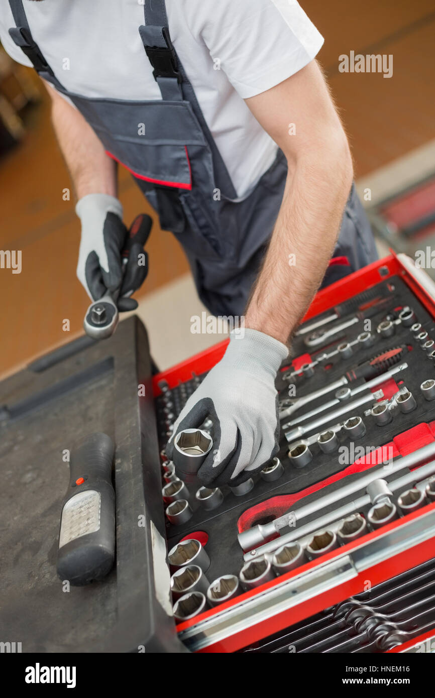Elevato angolo di vista meccanico maschio disponendo di strumenti nel cassetto di riparazione auto shop Foto Stock