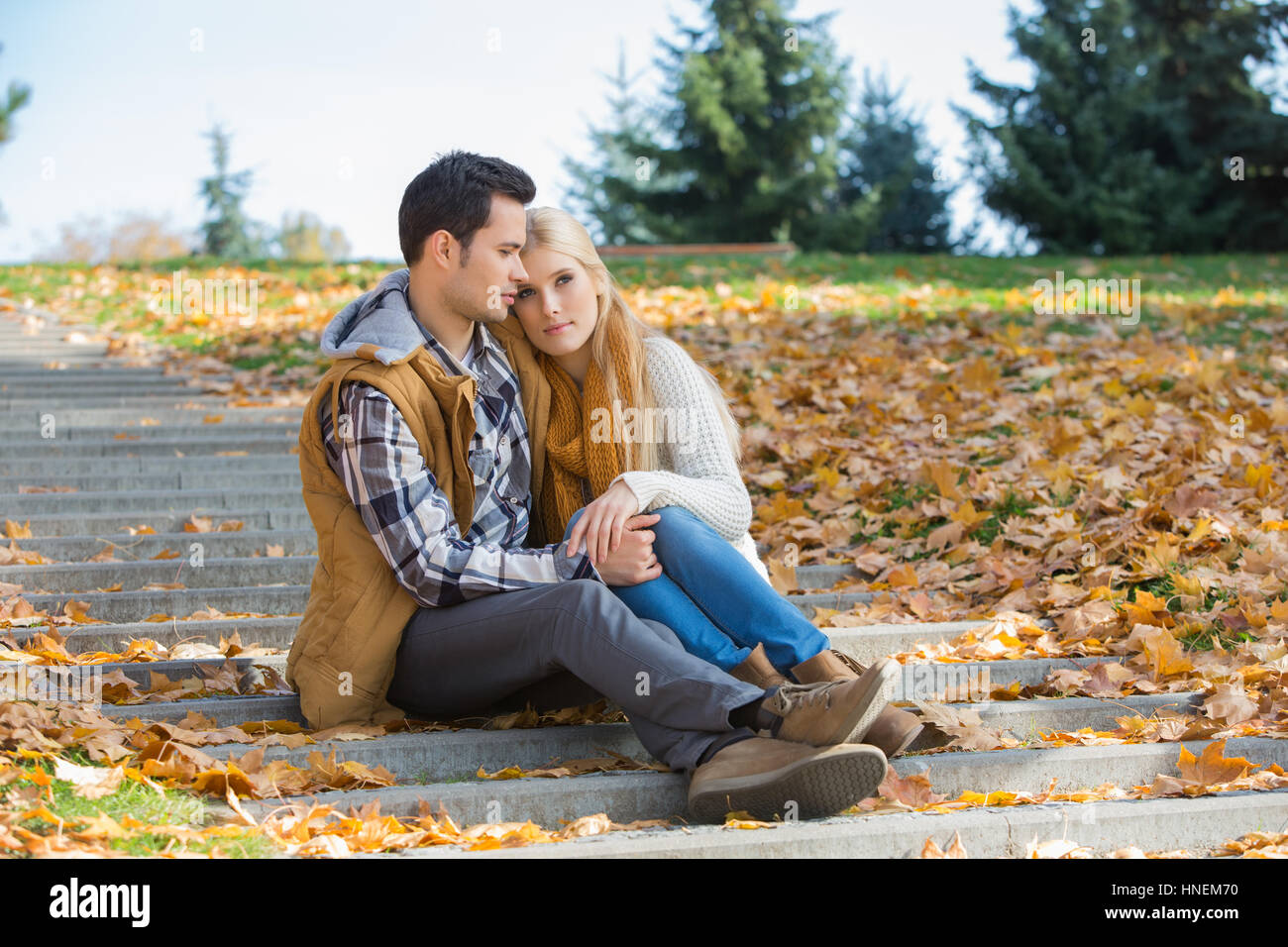 Amare giovane seduti insieme su passi nel parco durante l'autunno Foto Stock