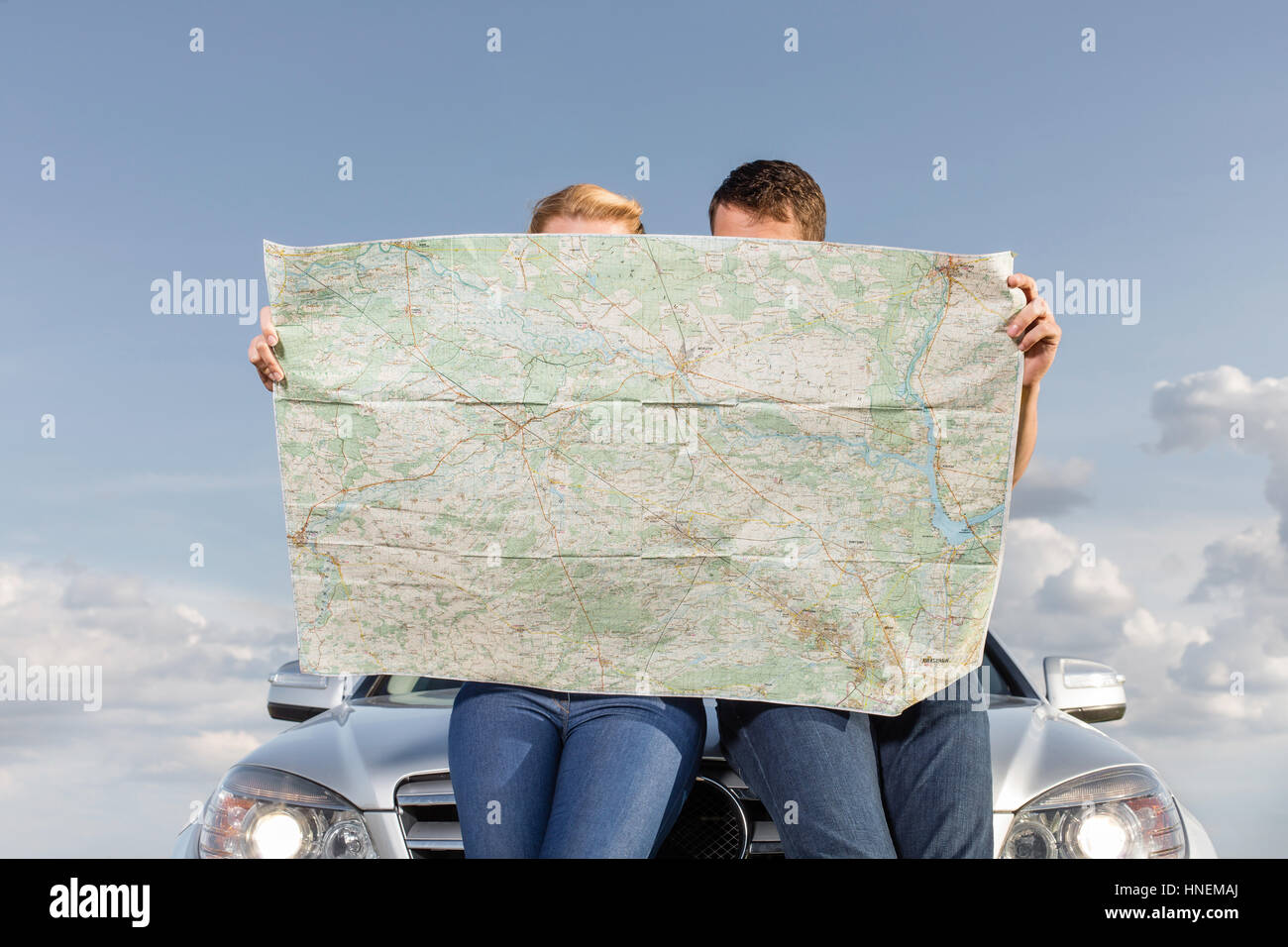 Paio di lettura mappa mentre appoggiata sul cofano auto durante il viaggio su strada Foto Stock