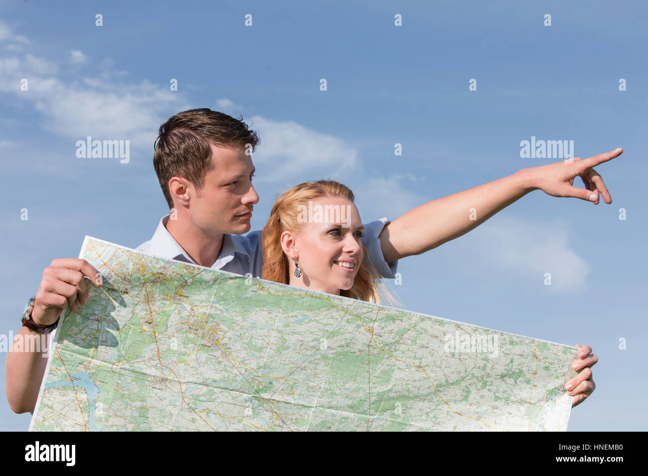 Donna che mantiene mappa mentre l uomo rivolto lontano contro sky Foto Stock