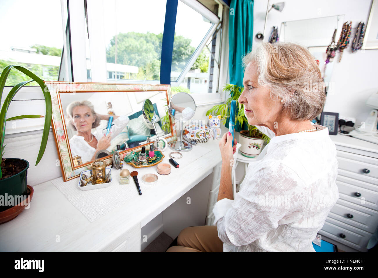 Senior donna pettinare i capelli a cassettiera in casa Foto Stock