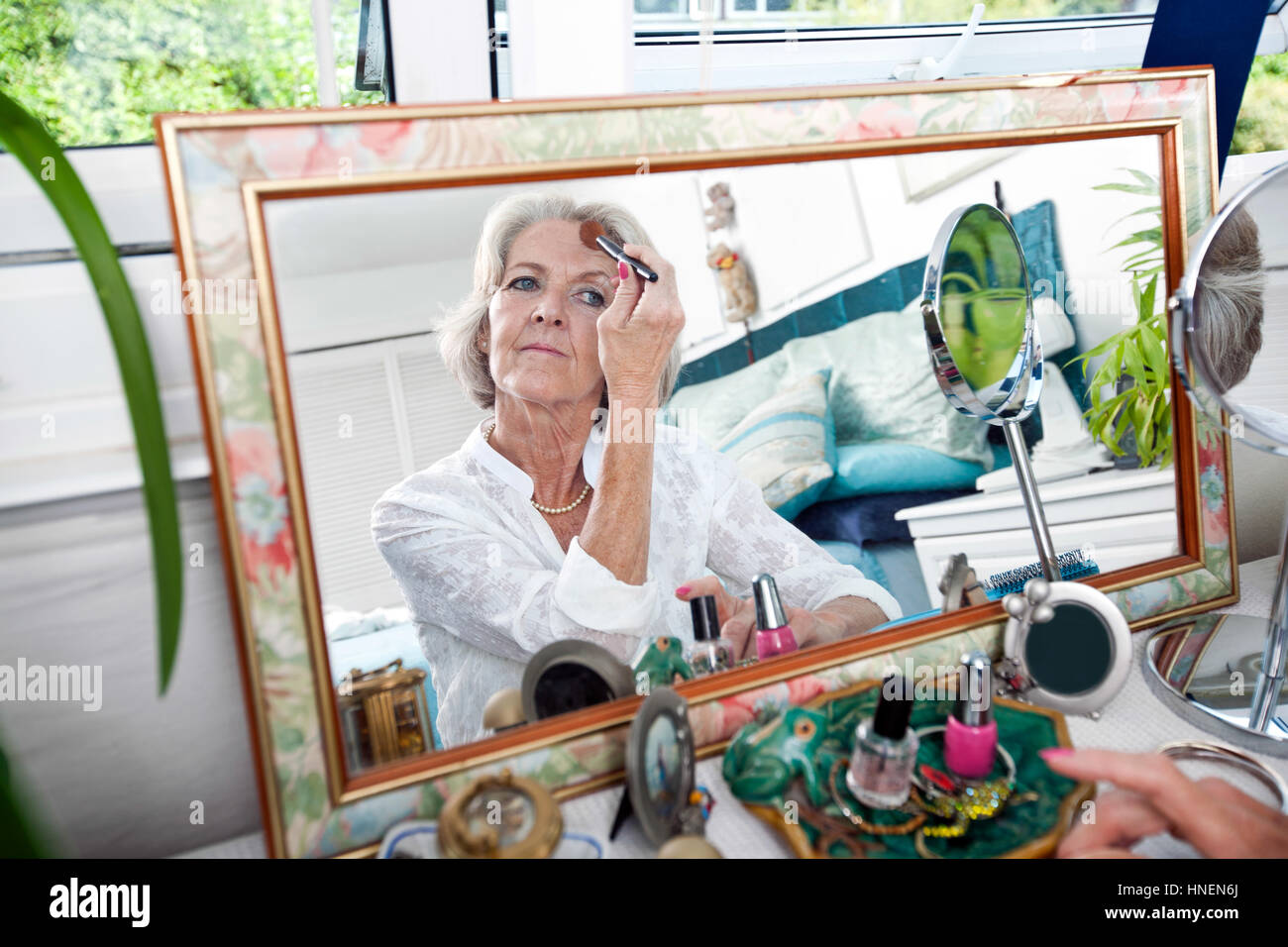 Specchio di riflessione senior donna applicando blusher a casa Foto Stock